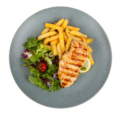 Grilled chicken breast, served with fries and salad on a gray plate. Pack shot. White background.