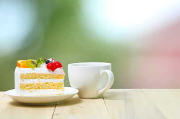 Slice cake with coffee cup on wood , green blur background