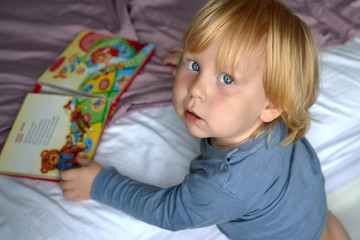 A child of three years old is watching a picture book