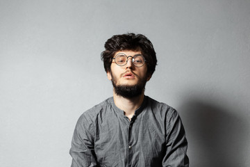 Fototapeta premium Portrait of self-confident bearded guy with disheveled hair and glasses, on background of grey.