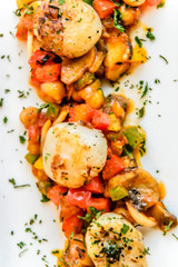 starter of seared scallops with tomato and zuchini salsa with herb and black pepper
