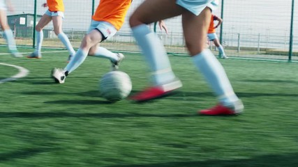 Low section shot of female soccer player dribbling ball on field and rival tripping her up - Powered by Adobe