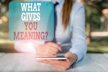 Writing note showing What Gives You Meaning Question. Business concept for your purpose or intentions in life Female business person sitting by table and holding mobile phone