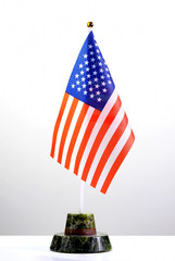 Tabletop American flag on a stone stand on a white table. The concept of a formal meeting of officials or businessmen.