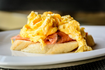 scrambled eggs on smoked salmon and baguette served on a white china plate