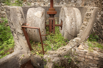 old olive press stone wheels in abandoned village of Palia Plagia, Greece