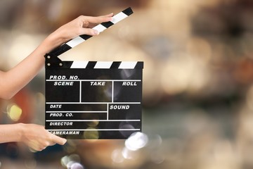 Cinema clapperboard in female hands on blue bokeh background