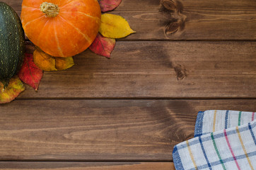 Copy space for Thanksgiving on a dark wooden background with pumpkin, autumn leaves and a napkin in...