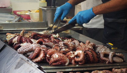 A chef cooks octopuses on a grill plate in the seafood restaurant