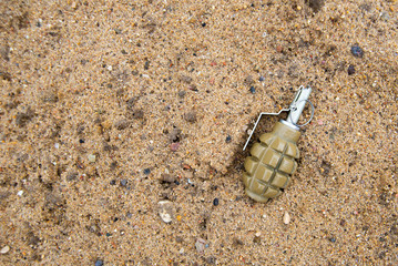 Hand grenade on sand background