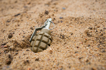 Hand grenade on sand background