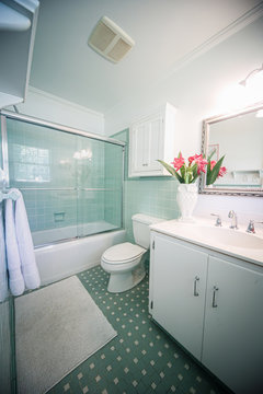 Small outdated tile bathroom with a clear glass door and a white cabinet sink vanity and mirror