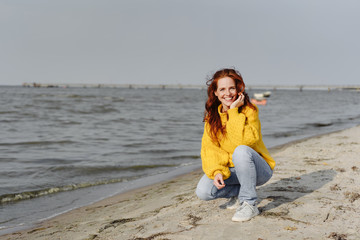 Friendly happy young woman crouching on a beach