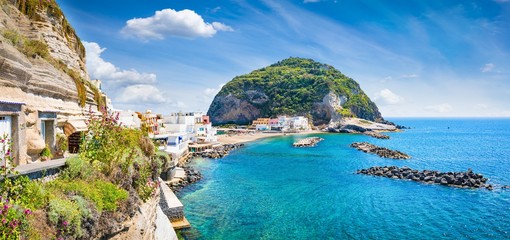 Beautiful coast of village Sant'Angelo, giant green rock in blue sea near Ischia Island, Italy.
