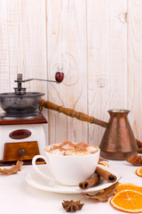 Cup of coffee with marshmallows and cocoa, leaves, dried oranges, spices, on a white background. Delicious hot autumn drink, morning mood. Copy space.