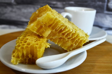 Honeycombs with honey and pollen on a white plate.