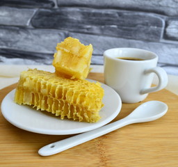 Honeycombs with honey and pollen on a white plate.