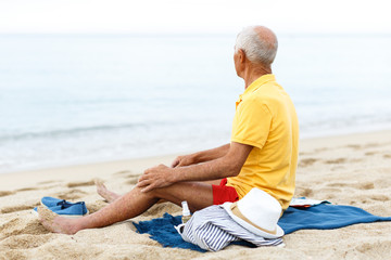 Happy man resting. Clothes on the sand near sea