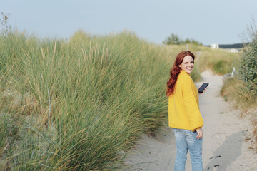 Happy woman walking along a sandy coastal path
