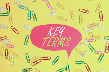 Handwriting text Key Terms. Conceptual photo Words that can help a demonstrating in searching information they need Flat lay above empty paper with copy space and colored paper clips
