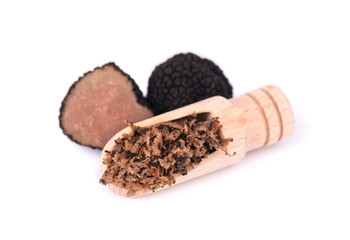 Grated Truffle on a wooden spoon. Fresh black truffles isolated on a white background. Delicacy exclusive truffle mushroom. Piquant and fragrant French delicacy. Clipping path.