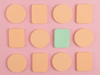 A lot of sponge, a beautiful blender for applying foundation or powder. Flat lay on a pink background, copy space.