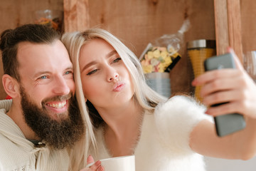 Morning family fun. Closeup portrait of couple drinking coffee in kitchen, using smartphone camera to take selfie.