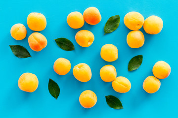 Apricots and leaves pattern on blue background top view