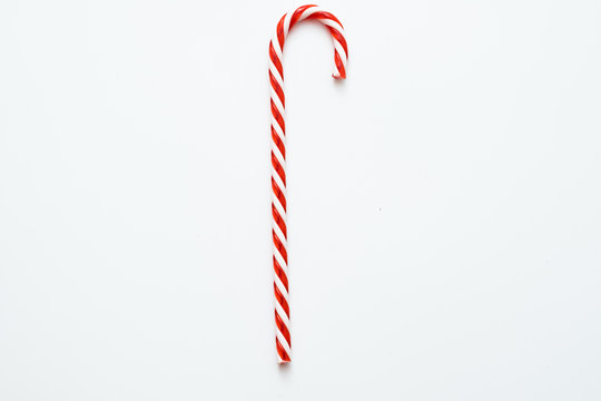 Traditional Christmas edible decoration. Flat lay of striped red candy cane isolated on white background. Copy space.