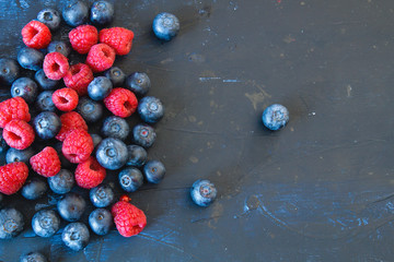 Fresh raspberries and blueberries on dark blue background