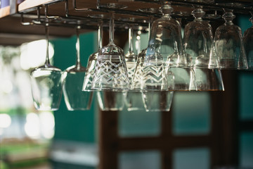 Vintage wine glasses hanging from a bar rack at a small rustic restaurant at sunset