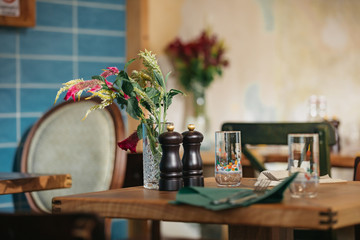 Detail of a wooden table set for dinner in a rustic indoors restaurant