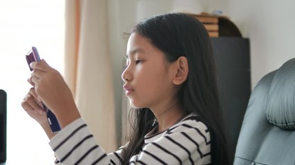 Little Asian girl playing smartphone select focus shallow depth of field