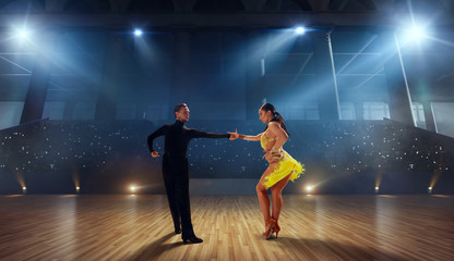 Fototapeta na wymiar Couple dancers perform latin dance on large professional stage. Ballroom dancing.