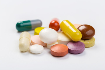 Assorted pharmaceutical medicine pills, tablets and capsules.Heap of assorted various medicine tablets and pills different colors on white background. Top view.Copy space