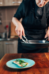 Female chef plating fried leeks on a toasted bread