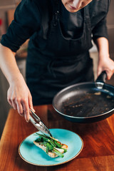 Female chef plating fried leeks on a toasted bread