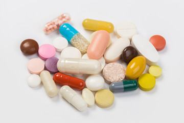 Assorted pharmaceutical medicine pills, tablets and capsules.Heap of assorted various medicine tablets and pills different colors on white background. Top view.Copy space