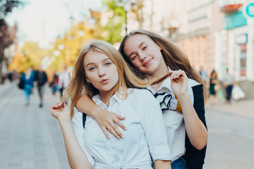 Happy brightful positive moments of two stylish girls hugging on street in city. Closeup portrait funny joyful attarctive young girls having fun, smiling, lovely moments, best friends.