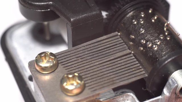 Music box mechanism rotates close-up on white background. Insides of music box during work. 4K video