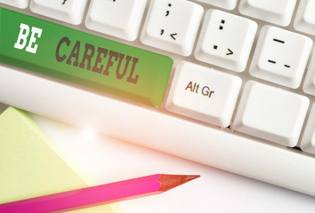 Conceptual hand writing showing Be Careful. Concept meaning making sure of avoiding potential danger mishap or harm White pc keyboard with note paper above the white background