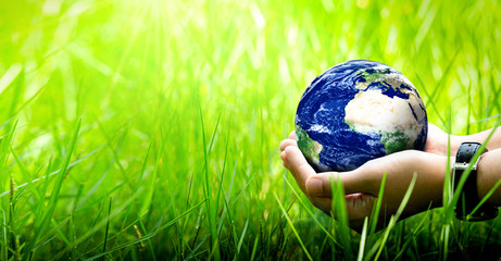 Woman hands holding world or globe above the field grass on earth day.Environment conservation and energy saving concept.Elements of this image are furnished by NASA.