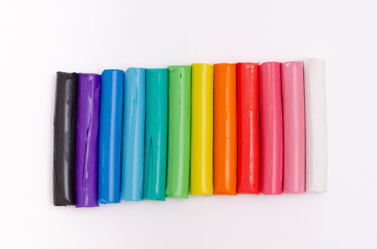 Multi-colored modelling clay stacked on a white background.