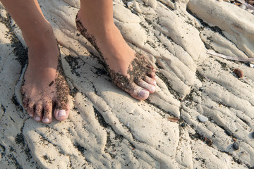 Beautiful female food with beach sand on a white beach rocky surface