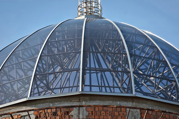 Element of architecture. Building on the blue sky background. Architectural construction of glass and metal beams. unfinished building. Glass dome on top of building.