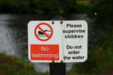 A no swimming sign beside a river 