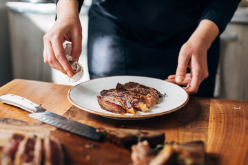 Female chef serving ribeye steak and cleaning the plate