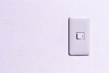 Simple light switch in room which is installed on the white coloured wall.