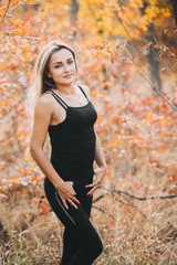 Beautiful attractive girl posing in autumn forest in black pants and t-shirt with beautiful white...