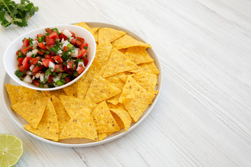 Pico de Gallo with gluten free tortilla chips on a white wooden background, side view. Copy space.